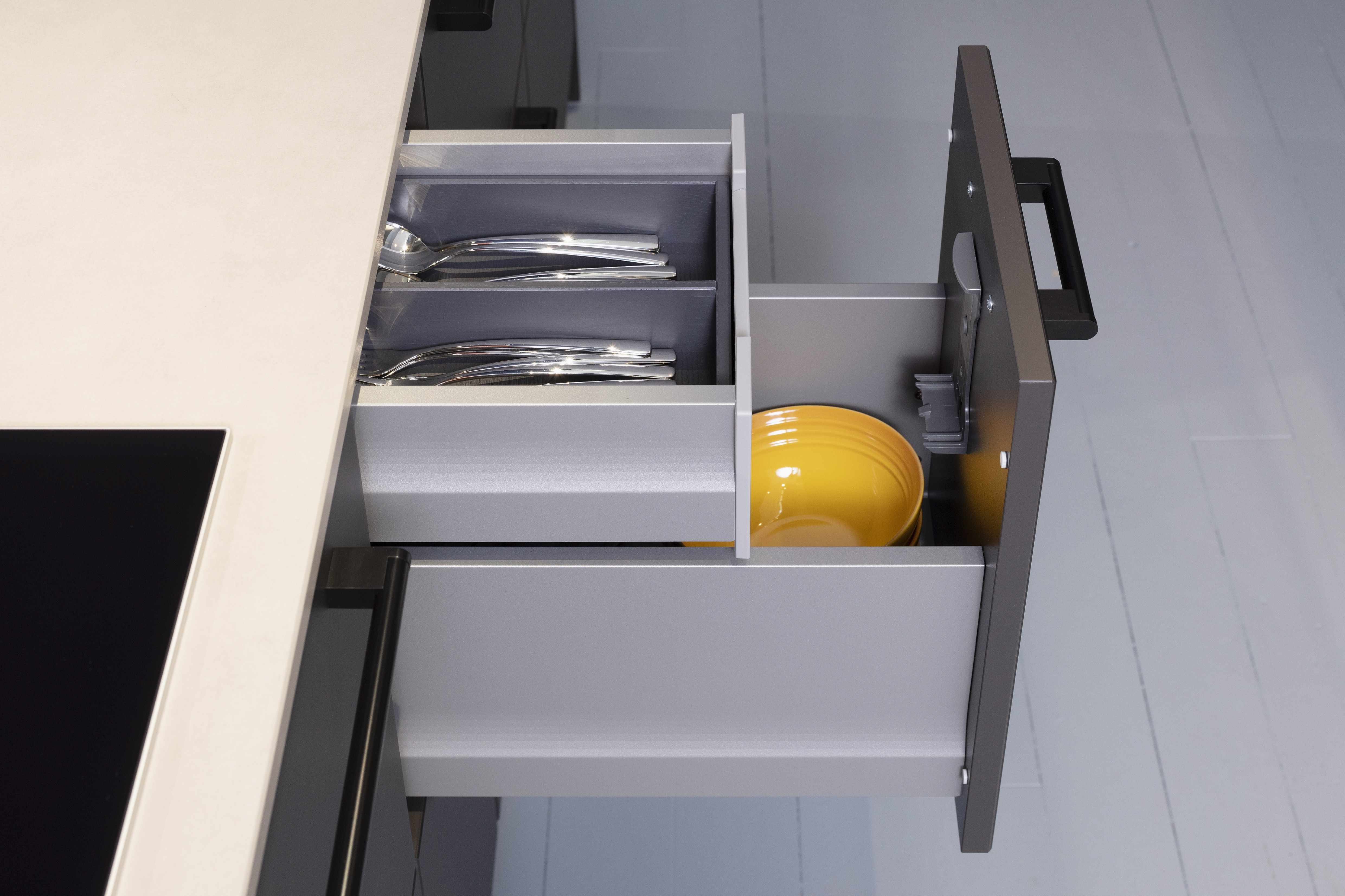 Concept130ART Front: SMART-GL Sandgrau metallic APL: SMART-GL Carbon metallic Geräte Blaupunkt Armatur und Spüle: Franke  Features: Insellösung mit Thekenfunktion mit Schubladen, Teppanyakiaufsatz für Kochfeld, Schubladen in Silber, Schubladen mit Griffmulde, Nischenlösung in Blau mit Regalfunktion.