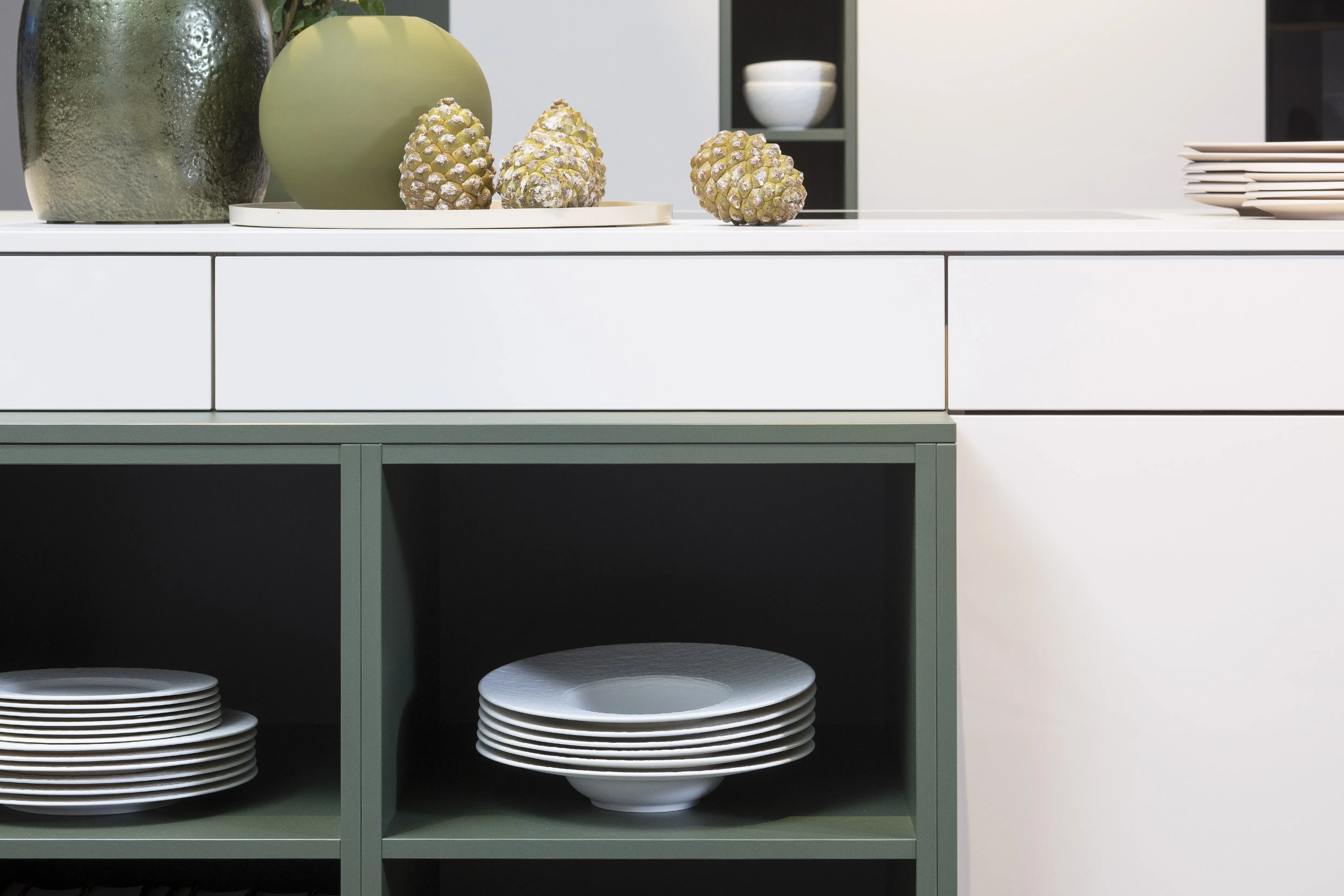 Concept130 Front: Perfect Sense Perfect Brillant Crema magnolia UV Hochglanz lackiert Front 2: Perfect Sense Scala Olivgrün Grüne Front? APL: Perfect Sense Crema Magnolia 16 mm Griff: Schwarz Metall matt Geräte: Blaupunkt Spüle und Armatur: Franke  Features: offene Regale in zweiter Frontfarbe abgesetzt, Apothekerschrank, Spüle in Schwarz.